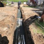Large Scale Commercial Sewage Treatment System - Multiple pipe trench being backfilled and compacted.